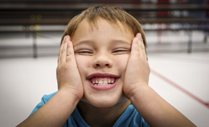 Young man smiles and holds his face in his hands
